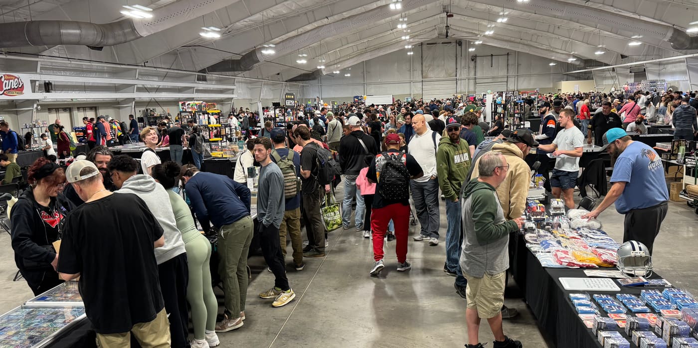 A long aisle of vendor tables with jerseys, memorabilia and display cases, collectors browsing shoulder to shoulder